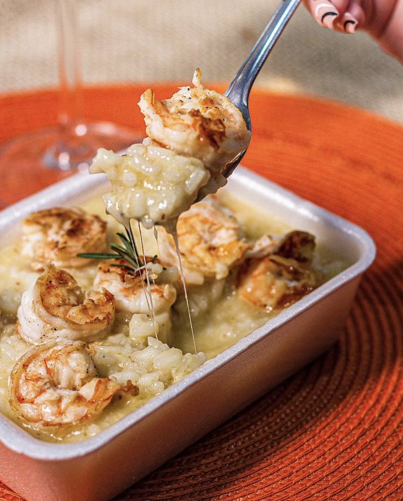 Risoto de camarão com queijo derretido puxando no garfo
